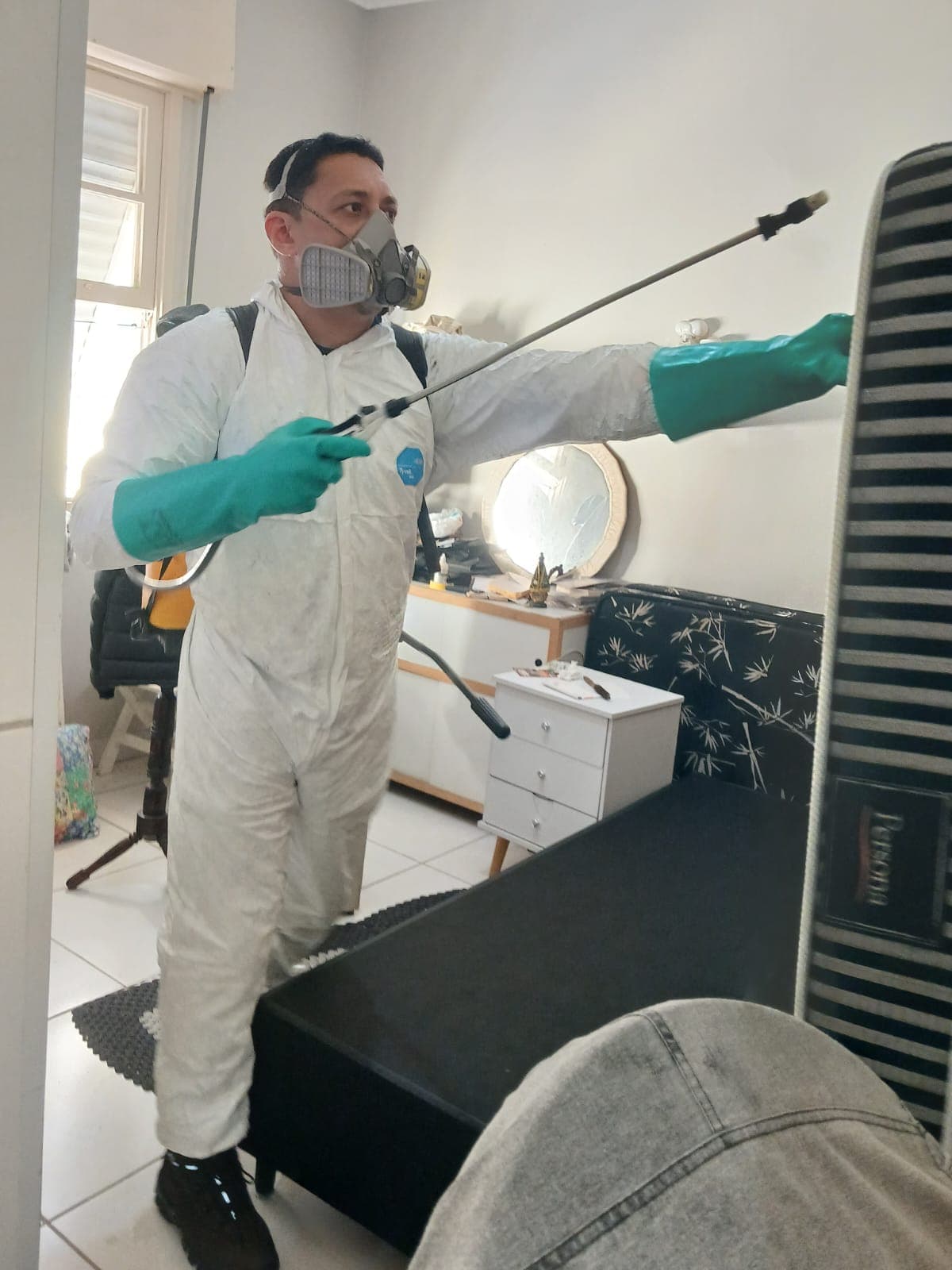 Profissional com EPI completo realizando aplicação técnica em ambiente residencial